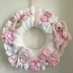 a pink and white wreath with stuffed animals on it