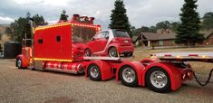 a red semi truck with a car on it's flatbed