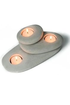 three lit candles sitting on top of two stone coasters in the shape of circles