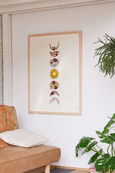 a living room with a couch, potted plant and framed artwork on the wall