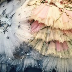 two different colored dresses are on display in a store window, one is made out of tulle and the other has sequins