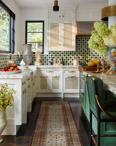 a kitchen with white cabinets and green chairs next to an area rug on the floor