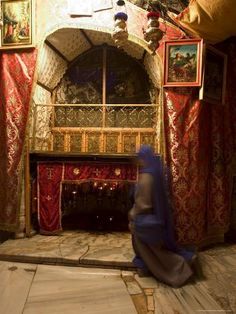 a person sitting on the floor in front of a fire place with red and gold curtains