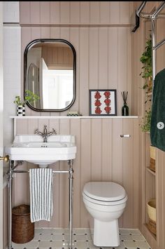 a white toilet sitting next to a bathroom sink under a mirror on top of a wall