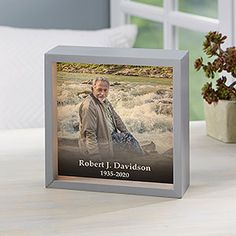 a silver frame with a photo of robert d davidson on it next to a potted plant