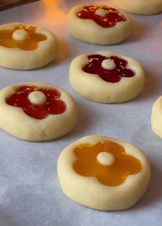 small cookies with jelly and cream fillings sitting on a baking sheet, ready to go into the oven