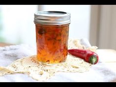 a glass jar filled with pickled vegetables on top of a white doily next to a red pepper