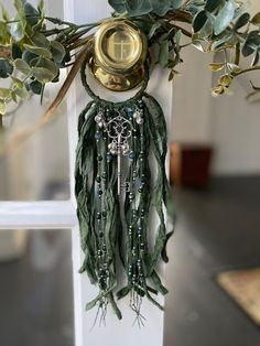 a close up of a clock on a pole with leaves and beads hanging from it