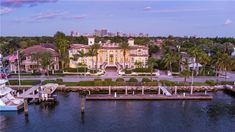 an aerial view of a waterfront home with boats in the water and palm trees surrounding it