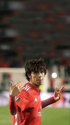 a soccer player with his arms out and hands in the air while standing on a field