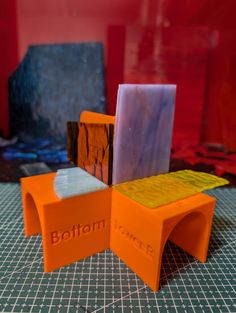 an orange and purple bench sitting on top of a table next to a red wall