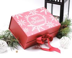 a red christmas gift box sitting on top of a white table