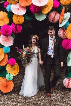 a bride and groom walking through an archway made out of paper fans