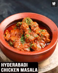 a red bowl filled with chicken masala on top of a wooden table next to a black background