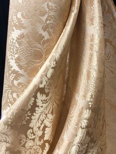 the fabric is gold and white with floral designs on it's side, as well as an intricate pattern