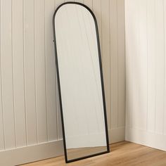 a tall mirror sitting on top of a wooden floor