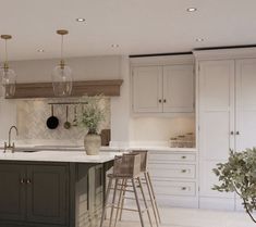 a large kitchen with an island and bar stools next to it, surrounded by white cabinets