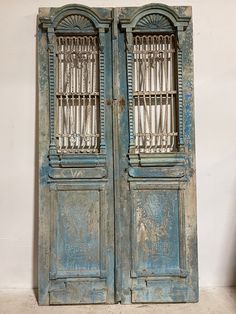 an old pair of doors with iron bars on the top and bottom, against a white wall