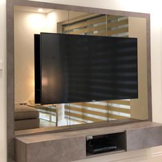 a flat screen tv mounted to the side of a wall in front of a mirror