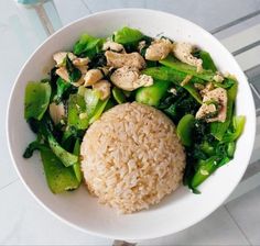 a white bowl filled with rice, broccoli and other vegetables on top of a table