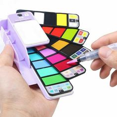 a hand holding a cell phone case with different colors on it and a pen in the other hand