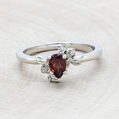 a close up of a ring with a stone on the top and leaves around it