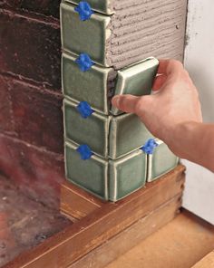 a person is placing blue stars on the side of a brick wall in front of a window