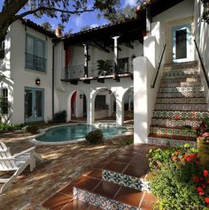 a house with a pool in the front yard and stairs leading up to it's second story