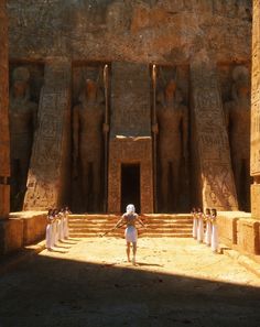 an egyptian temple with statues and people standing in front of the doorways to it