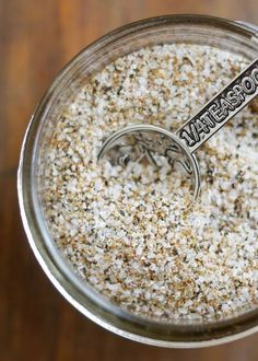 a jar filled with some kind of food on top of a wooden table next to a spoon