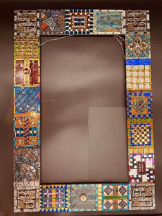 a multicolored mosaic photo frame with an empty square in the middle and a brown background