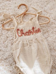 Cream colored romper with tie shoulder straps with personalized name embroidery. May add an additional flower design. Please choose yarn color and leave the name in the custom box. Yarn colors come in white, pink, fig, mustard, taupe, copper, blue, rose. Care: Handwash with mild soap and lay flat to dry for best results. Fig Mustard, Embroidery Sweaters, Clothing Embroidery, Children Outfits, Machine Applique Designs, Rose Care, Embroidery Tshirt, Name Embroidery, Embroidery Sweater