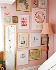 a room with pink walls and lots of pictures on the wall, including a mirror