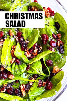 a salad with spinach leaves, cranberries and walnuts on top in a glass bowl