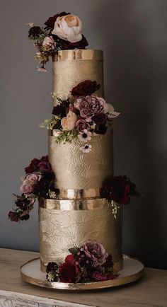 a three tiered gold wedding cake with flowers on top