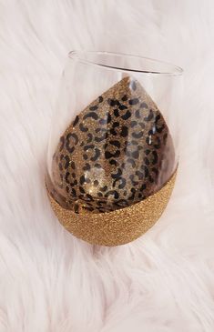 an animal print glass with gold glitter on the bottom sits on a white fur covered surface