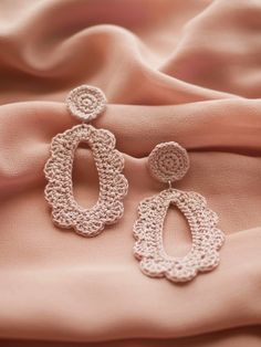 two pairs of crocheted earrings on pink fabric