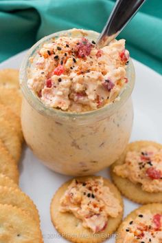 crackers and dip in a jar on a white plate with blue napkin behind it