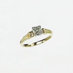 a yellow gold ring with two diamonds on the top and bottom, sitting on a white surface