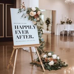 a sign that says happily ever after sitting on the floor next to some flowers and greenery