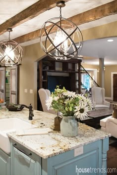 an image of a kitchen island with flowers in the center and chandelier above it