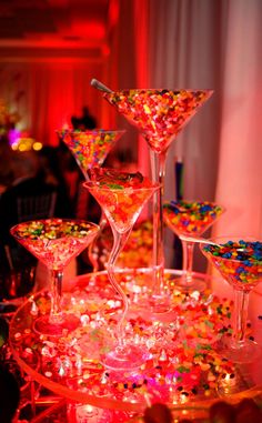 a bunch of glasses that are sitting on a table with confetti in them