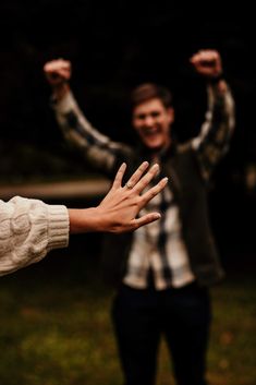 two people standing in the grass with their hands up