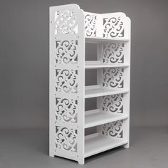 a white book shelf with intricate carvings on the top and bottom shelves, against a gray background