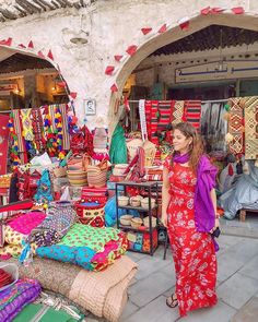 a woman standing in front of a store filled with colorful items