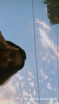 a man with long hair standing next to a telephone pole and looking up at the sky