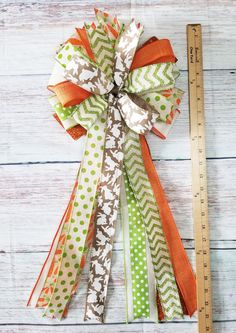 an orange, green and white bow with polka dots on it next to a ruler