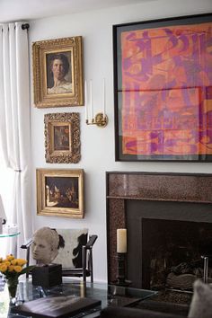 a living room filled with furniture and paintings on the wall above a fire place in front of a fireplace