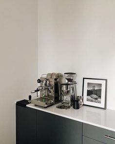 a coffee maker sitting on top of a counter next to a framed photograph and other items