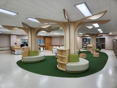 an office with circular seating and green carpeted flooring in front of two large bookshelves